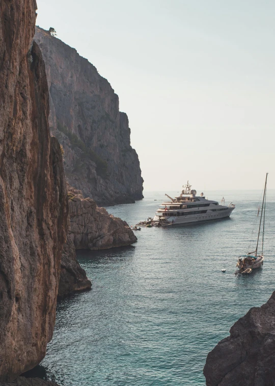 a couple of boats that are in the water, by Daniel Seghers, pexels contest winner, renaissance, steep cliffs, on a super yacht, high angel distant shot, cinematic still