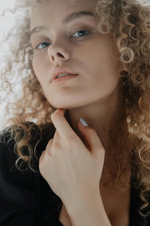 a woman with curly hair posing for a picture, trending on pexels, renaissance, close-up of thin soft hand, hand on her chin, curated collection, fashion model portrait