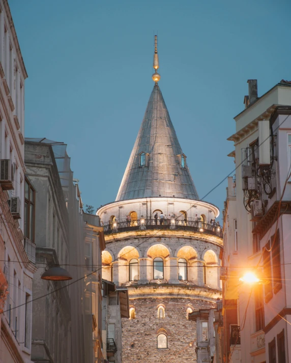 a tall tower sitting in the middle of a city, unsplash contest winner, art nouveau, turkish and russian, evening lights, pointy conical hat, profile image