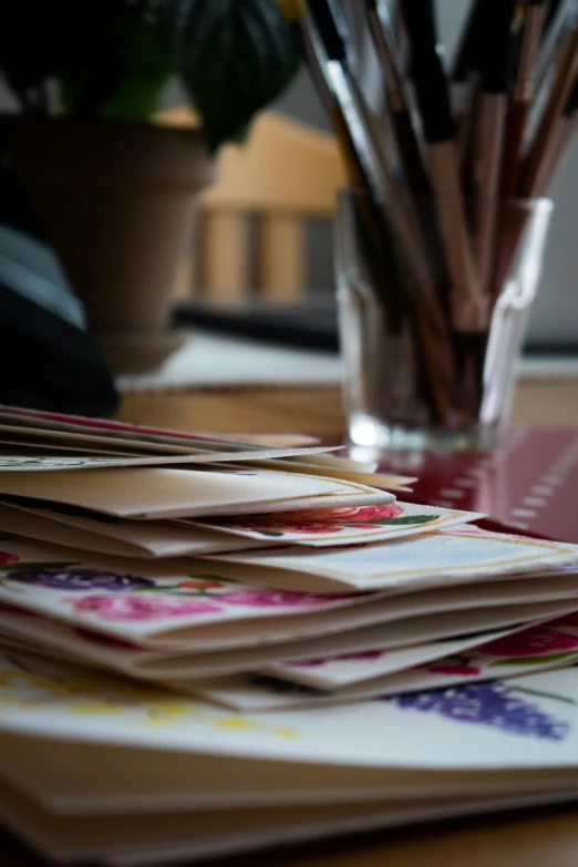 a stack of cards sitting on top of a wooden table, unsplash, mail art, stitching, delightful surroundings, flowers, traditional