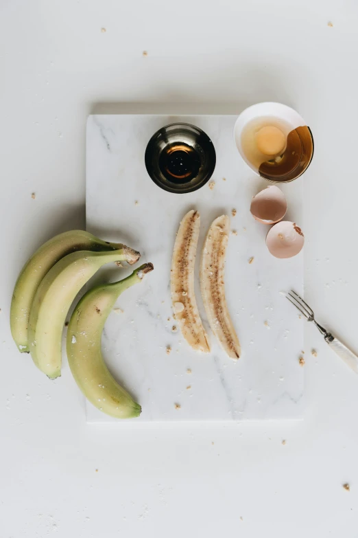 a cutting board with bananas and eggs on it, by Nicolette Macnamara, dwell, battered, sugar, mix