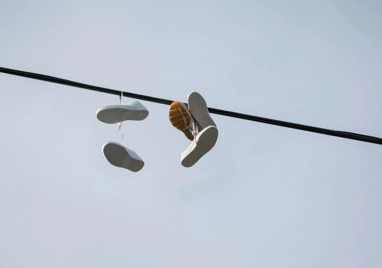 a pair of shoes hanging from a power line, by Jan Rustem, postminimalism, spores floating in the air, white, concert, kickflip