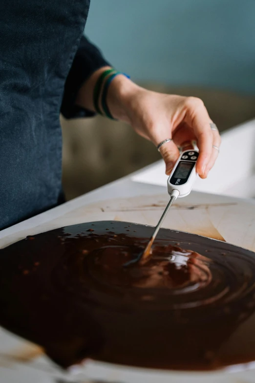 a woman is making a chocolate cake with a spatula, by Matthias Stom, trending on pexels, process art, made of liquid, holding scale, top down photo, programmable black goo