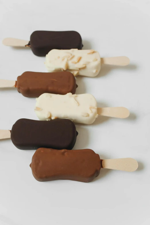 a group of ice cream pops sitting on top of each other, browns and whites, fully chocolate, matte finish, thumbnail