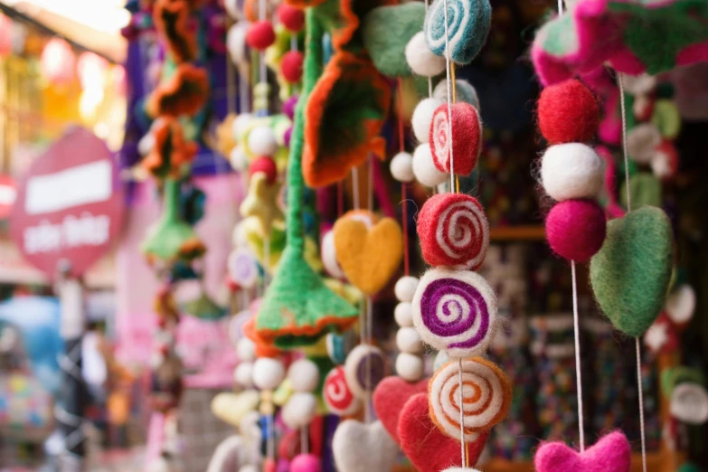 a bunch of hearts hanging from strings in a store, pexels, folk art, made of felt and cloth and beads, street vendors, swirls, needle felting