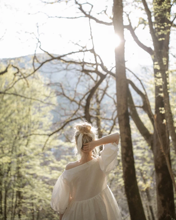 a woman in a white dress standing in the woods, unsplash contest winner, light and space, nice spring afternoon lighting, in the mountains, taken in the late 2010s, wearing simple robes