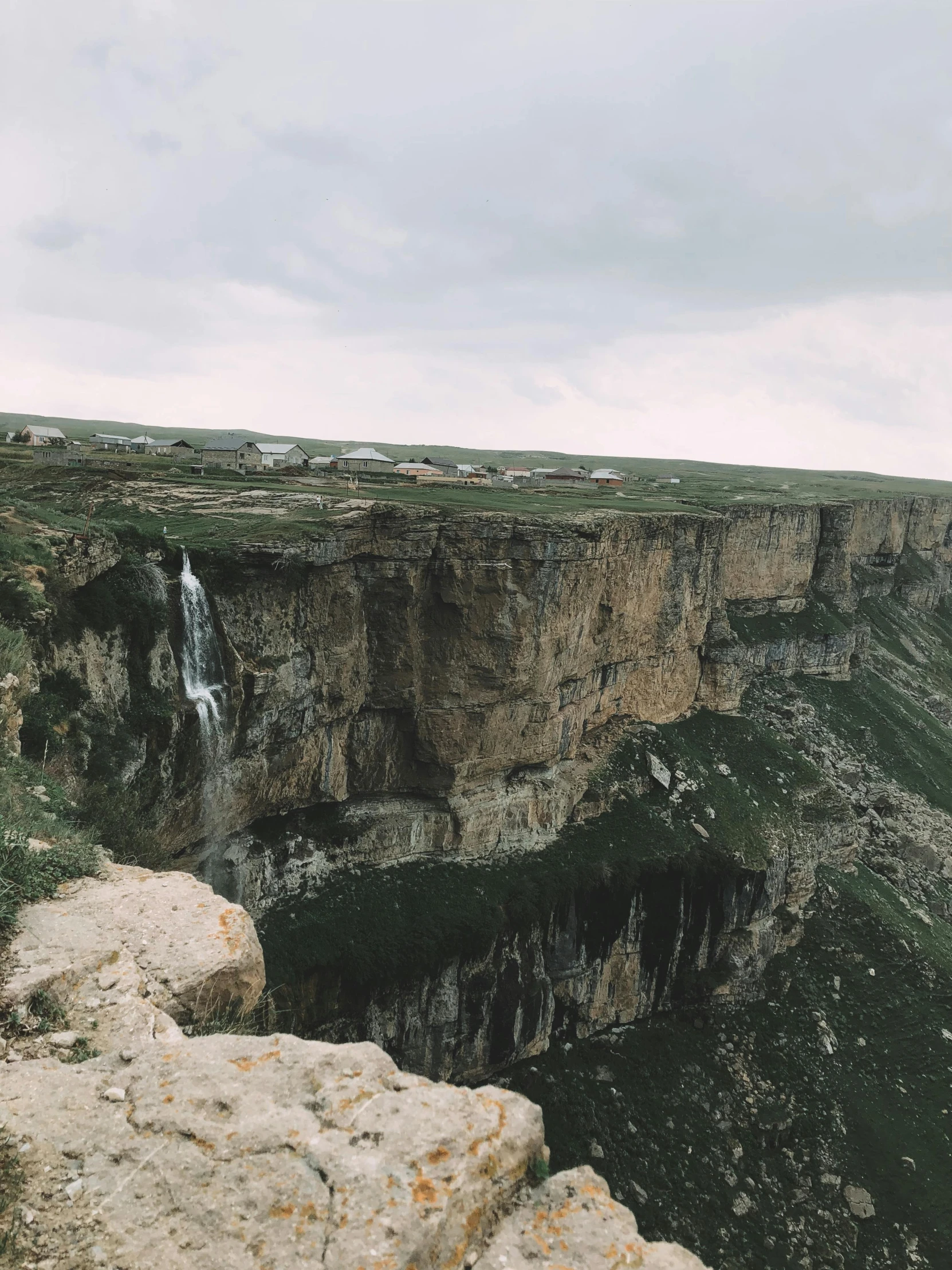 a man standing on top of a cliff next to a waterfall, by Muggur, pexels contest winner, les nabis, marsden, panorama view, low quality photo, high angle view