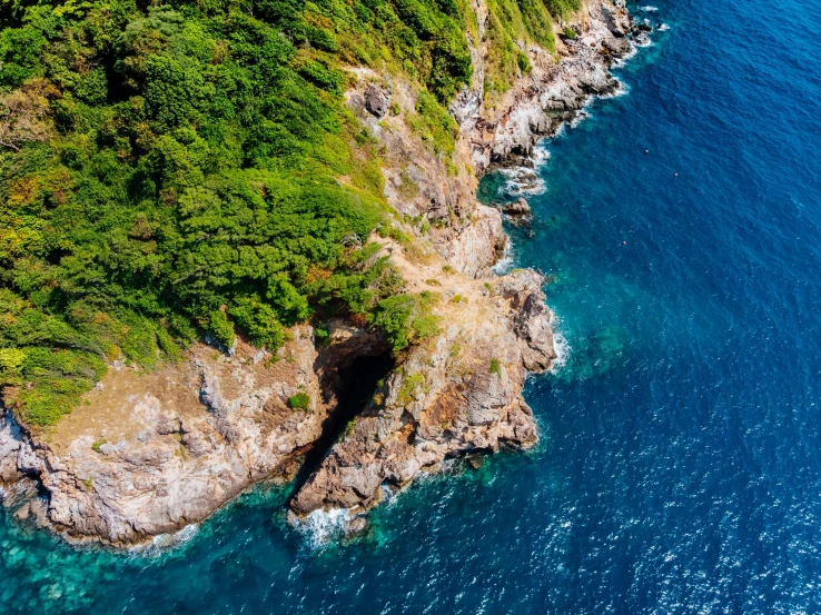 a large body of water next to a lush green hillside, pexels contest winner, figuration libre, island with cave, aerial footage, rocky coast, conde nast traveler photo