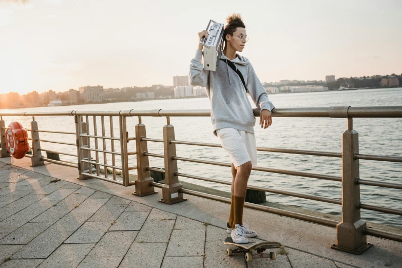 a man riding a skateboard down a sidewalk next to a body of water, a picture, louise zhang, wearing adidas clothing, kano tan'yu, humans of new york