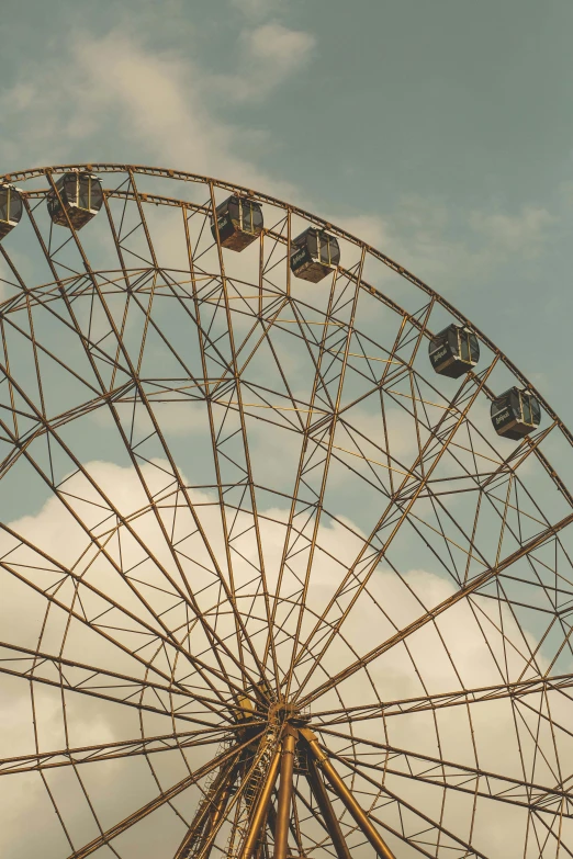 a ferris wheel in front of a cloudy sky, an album cover, inspired by Elsa Bleda, unsplash contest winner, romanticism, vintage muted colors, sunfaded, 2022 photograph, detail shot