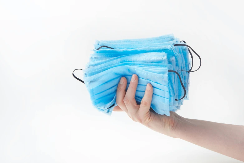 a person holding a bunch of blue surgical masks, on a white background, rectangle, 1x, stacks