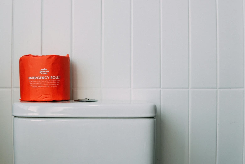 a toilet with a roll of toilet paper on top of it, inspired by Sarah Lucas, pexels contest winner, vibrant orange, urine collection bag, shot on leica sl2, looking off to the side