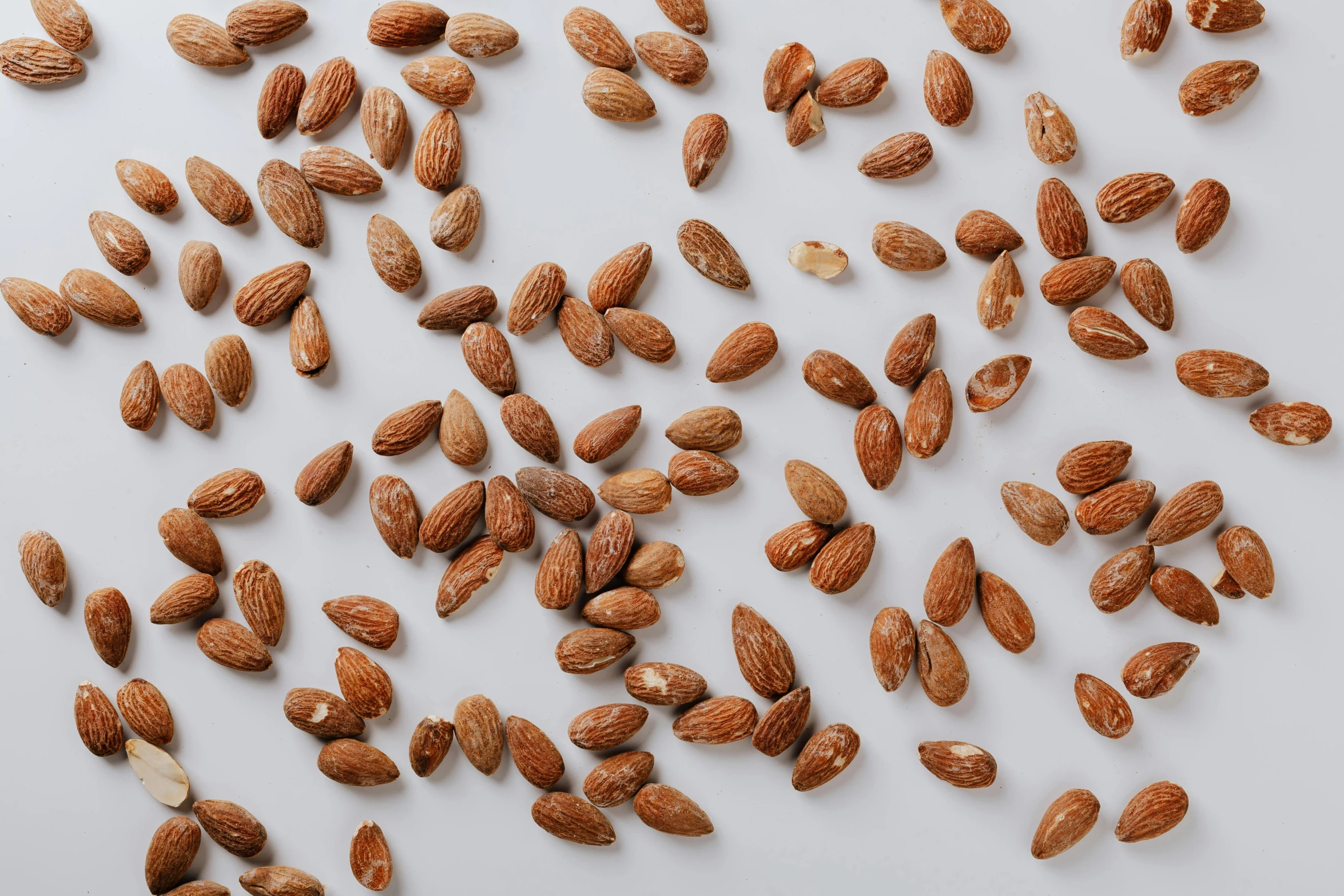 a pile of almonds on a white surface, by Carey Morris, trending on pexels, hemp, background image, 1 6 x 1 6, miniature product photo