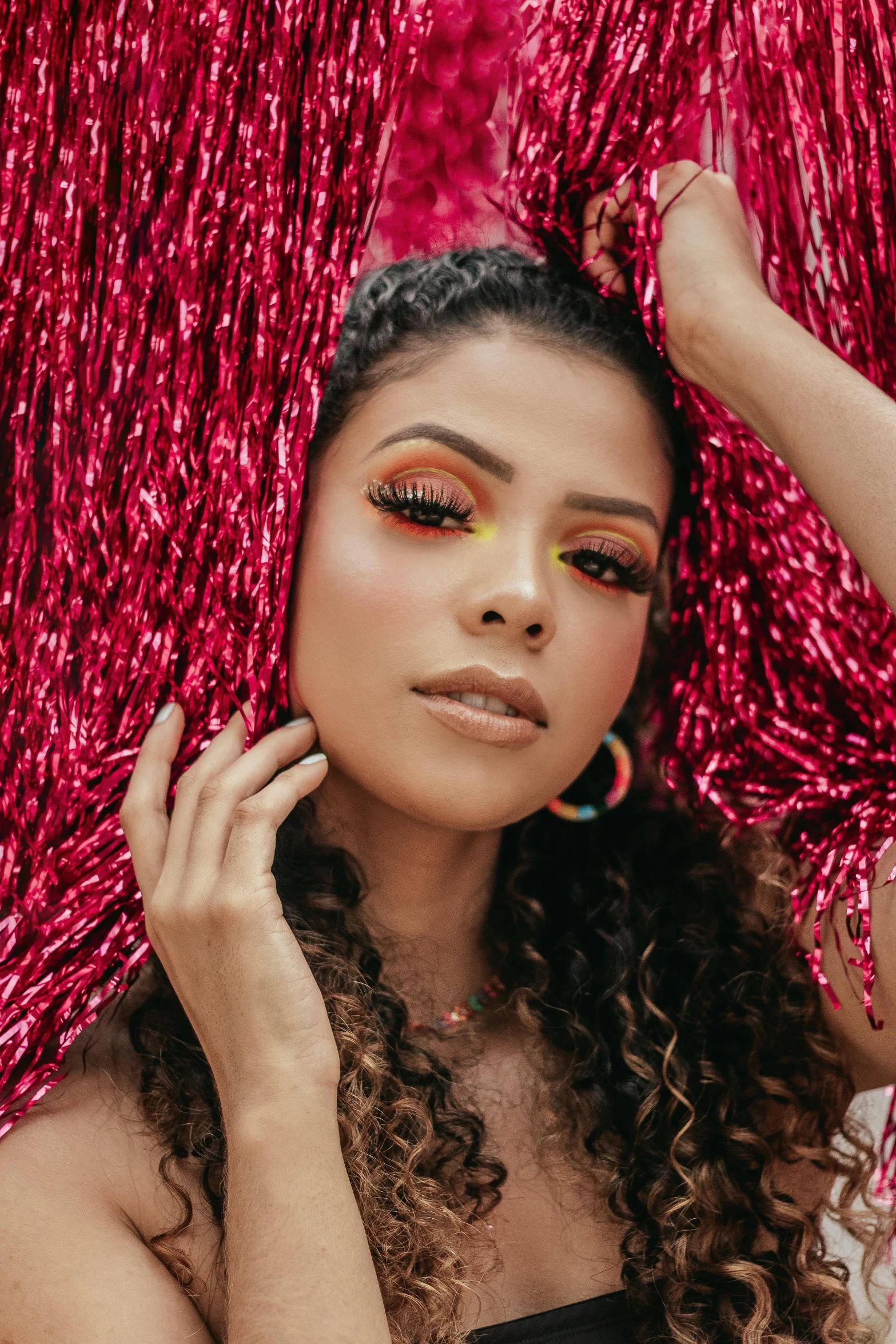 a woman with curly hair standing in front of a pink curtain, trending on pexels, renaissance, yellow and red color scheme, latina skin, glitter, colombian