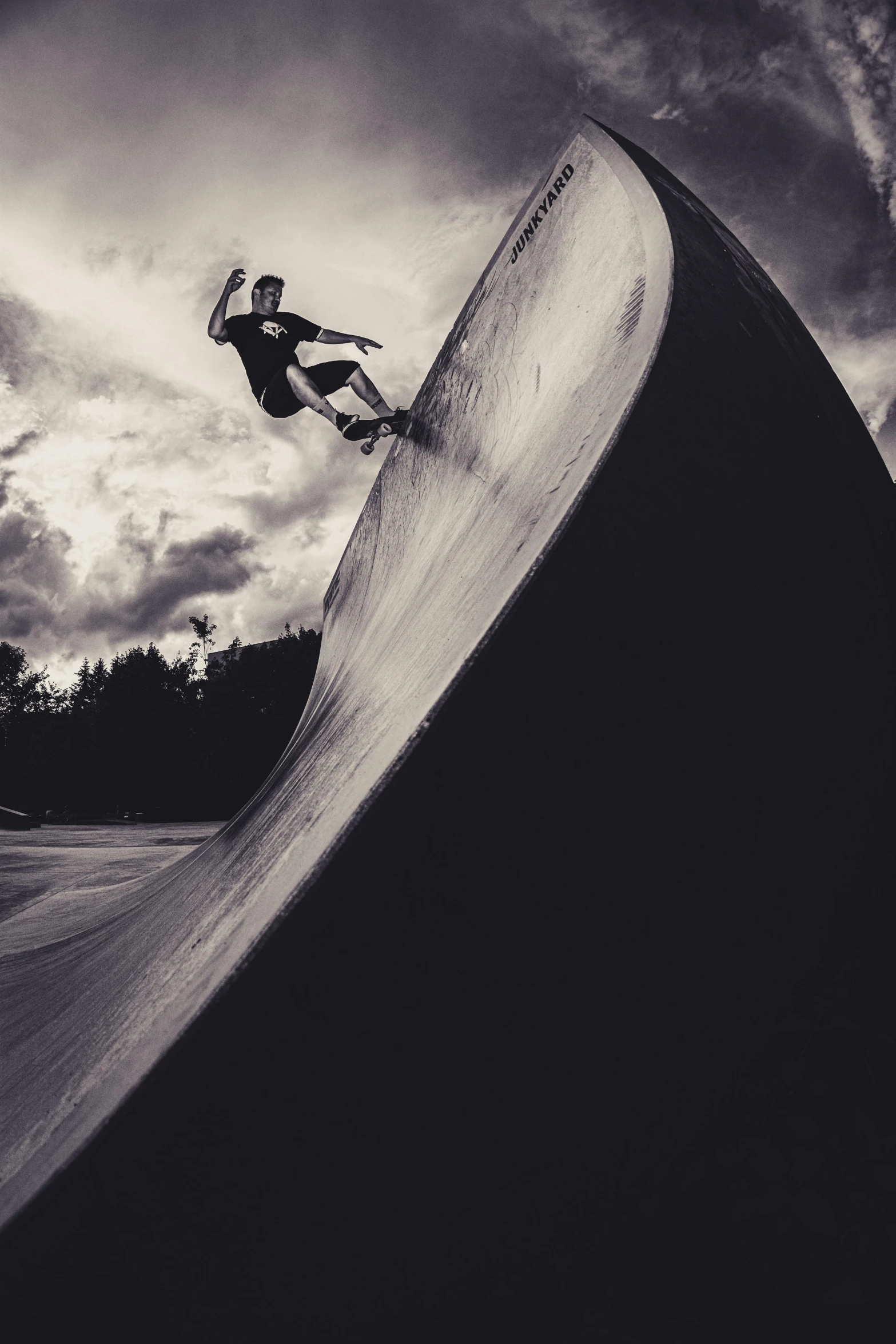 a man riding a skateboard up the side of a ramp, a black and white photo, unsplash contest winner, surfing a barrel wave, sepia photography, woamn is curved, profile pic