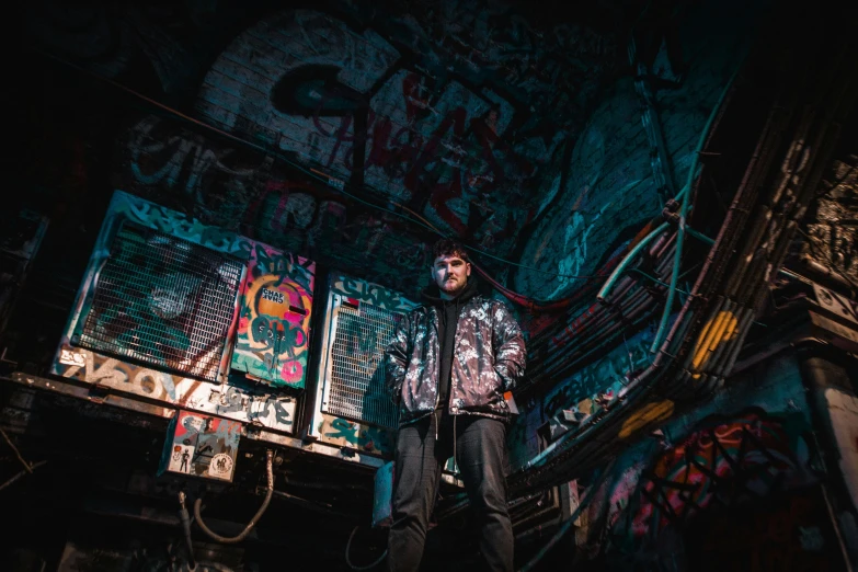 a man standing in front of a graffiti covered wall, cyberpunk art, by Micha Klein, pexels contest winner, graffiti, cyberpunk basement, dilapidated neon signs, cinematic outfit photo, instagram picture