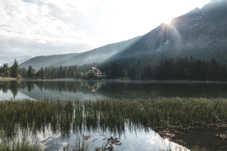 a lake with a mountain in the background, by Sebastian Spreng, pexels contest winner, renaissance, hazy light rays, lake house, sunflare, build in a forest near of a lake