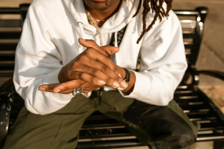 a man with dreadlocks sitting on a bench, trending on pexels, photo of a hand jewellery model, wearing a track suit, with index finger, wearing a white button up shirt