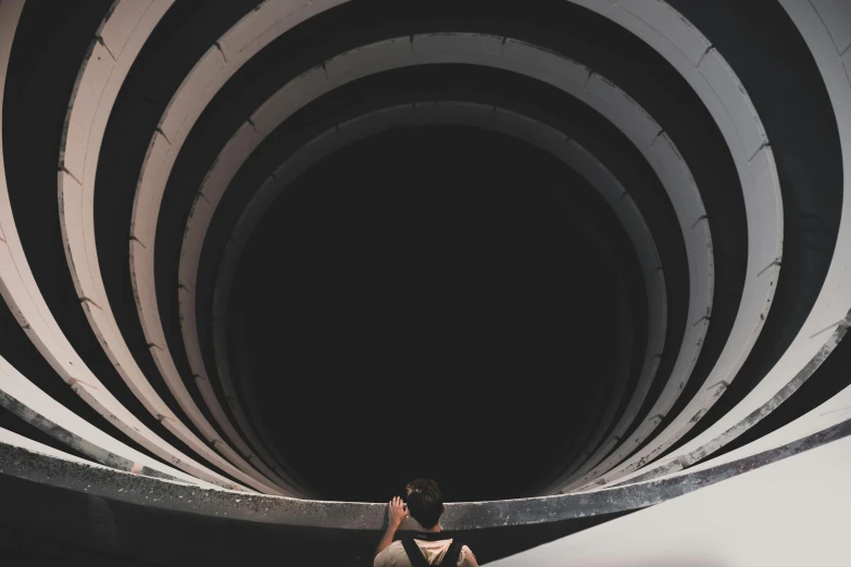a man standing inside of a black and white tunnel, inspired by Beeple, pexels contest winner, interactive art, spirals, instagram post, large pipes, plain background