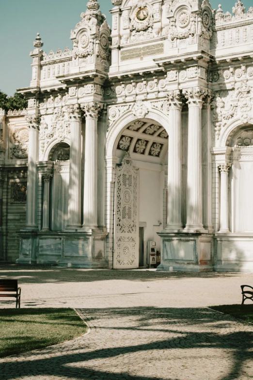 a couple of benches sitting in front of a building, a marble sculpture, pexels contest winner, neoclassicism, archway, istanbul, huge gate, opalescent palace