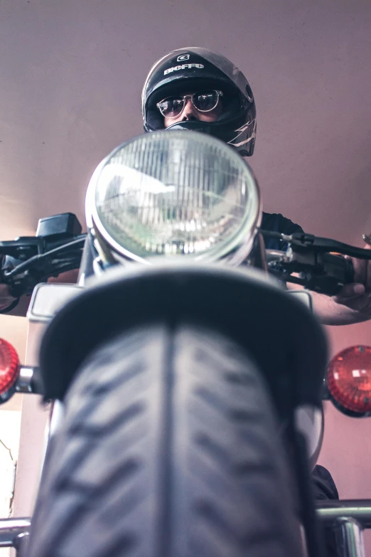 a man riding on the back of a motorcycle, trending on unsplash, photorealism, looking up at camera, indoor shot, low colour, head macro