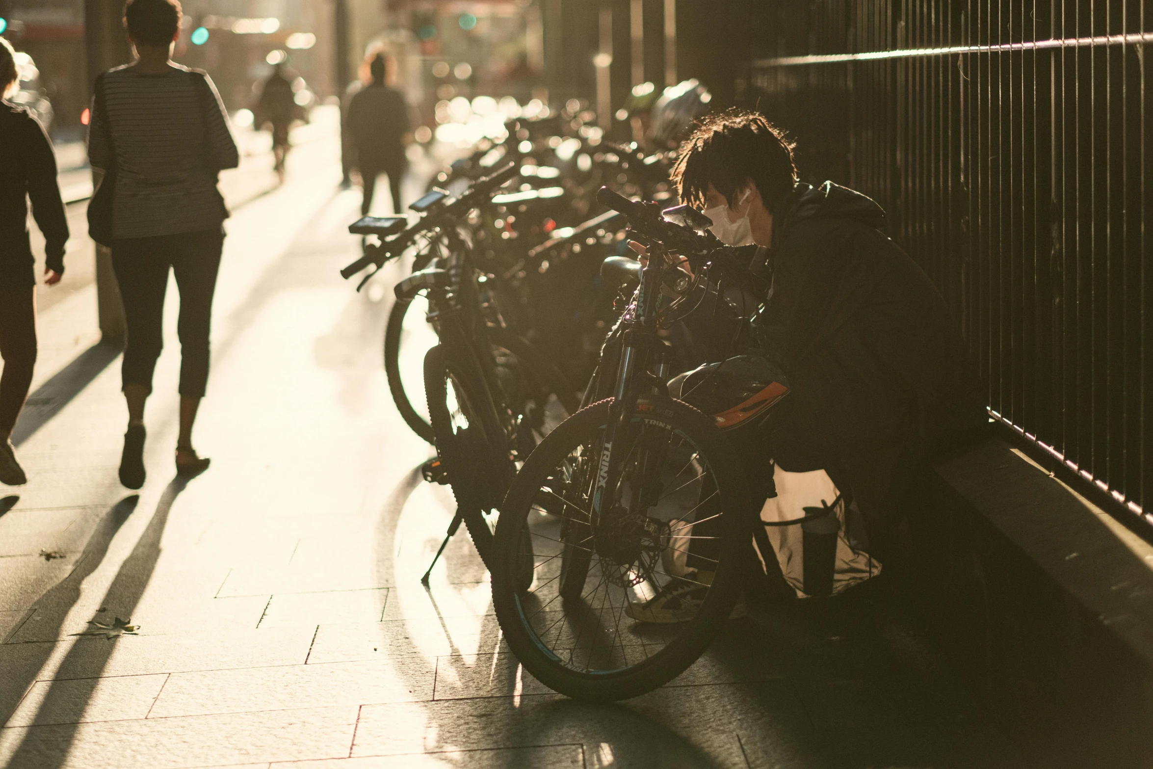 a man sitting on a bench next to a row of bikes, pexels contest winner, melbourne, face down, warm light, student