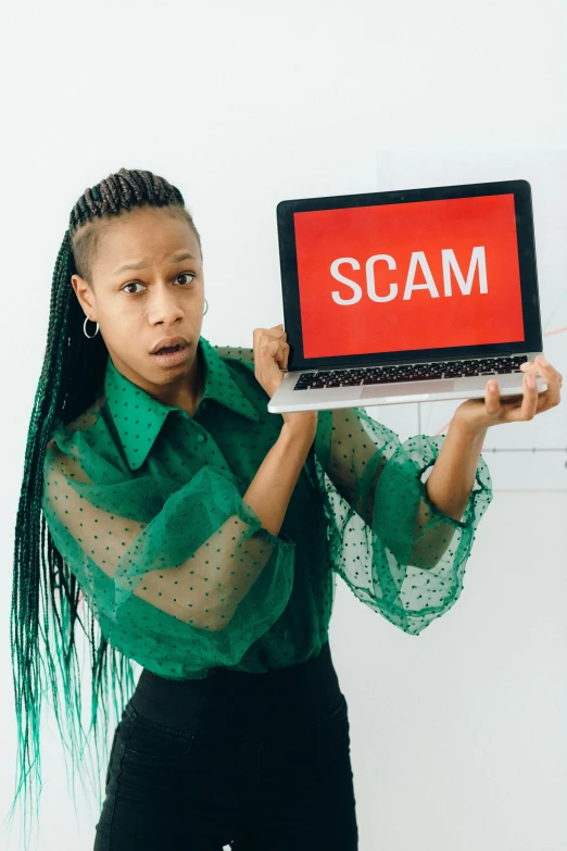 a woman holding a laptop with the word scam on it, an album cover, by Dulah Marie Evans, trending on pexels, computer art, looking threatening, aida muluneh, instagram post, studio photo