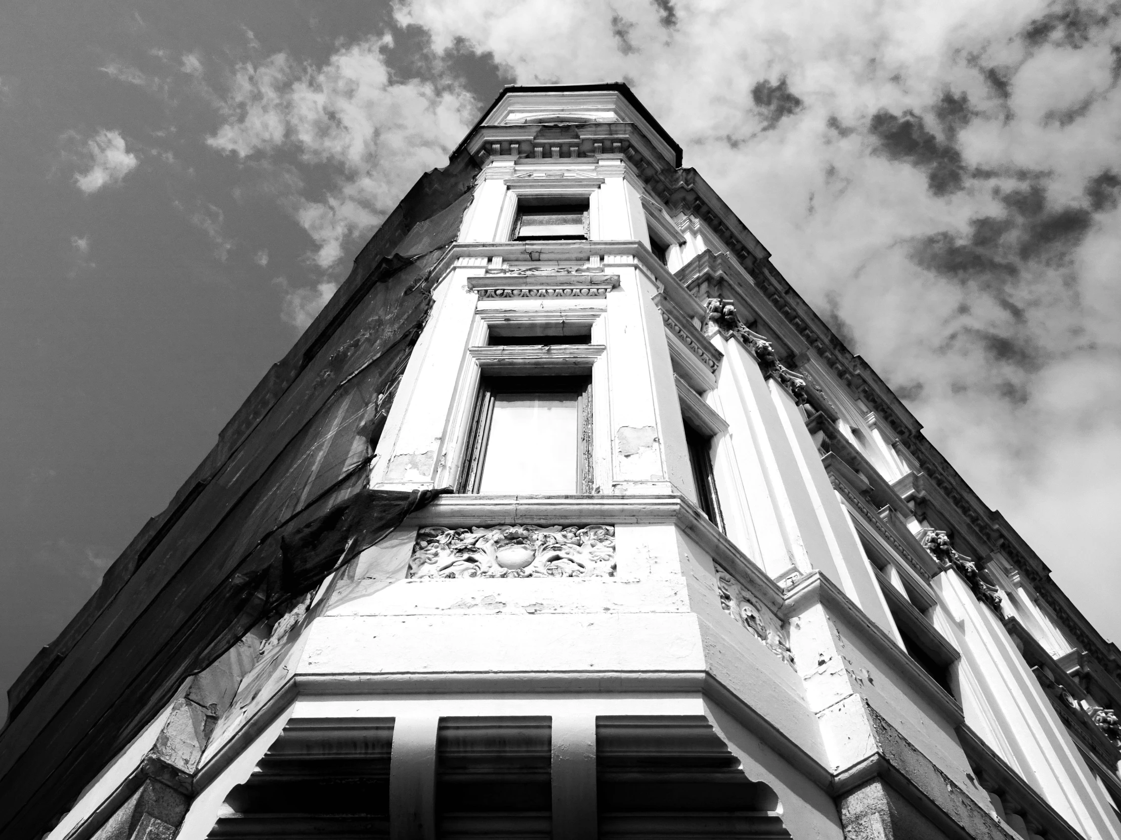 a black and white photo of a tall building, a black and white photo, unsplash, baroque, an abandoned old, corners, blue sky, high details photo