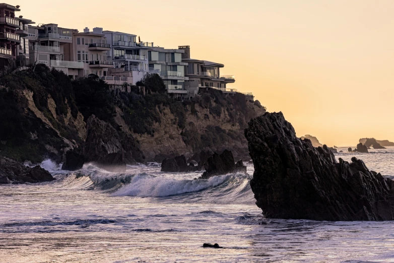 a person riding a surfboard on top of a wave, by Doug Wildey, pexels contest winner, renaissance, cliffside town, house on a hill, late afternoon, jagged rocks