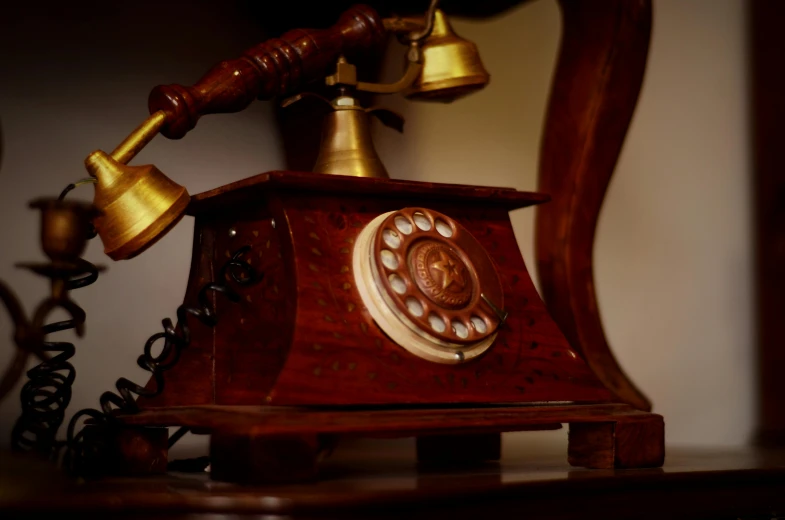 a telephone sitting on top of a wooden table, holding a bell, at night