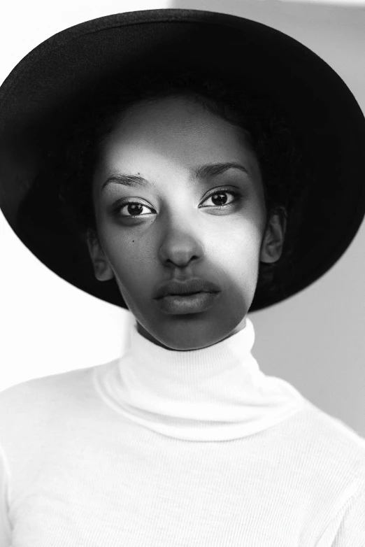 a black and white photo of a woman wearing a hat, a black and white photo, inspired by Afewerk Tekle, in white turtleneck shirt, androgynous person, brown skin. light makeup, wide forehead