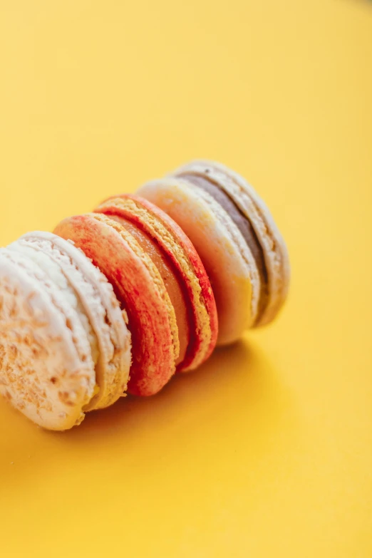 a stack of macarons sitting on top of a yellow table, pexels, rococo, orange and white color scheme, multiple stories, sugar, yellow red scheme