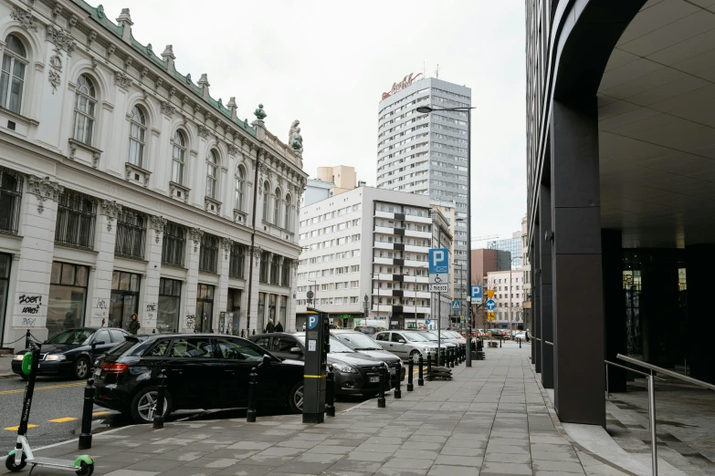 a city street filled with lots of parked cars, a photo, by Emma Andijewska, pexels contest winner, bauhaus, tall buildings on the sides, located in hajibektash complex, фото девушка курит, helsinki