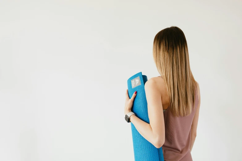 a woman holding a yoga mat in her hands, by Carey Morris, minimalism, angled shot, light-blue, over the shoulder, a medium shot