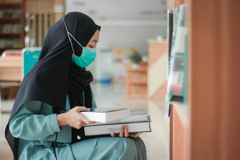 a woman wearing a face mask reading a book, hurufiyya, at college, pharmacy, colour corrected, nursing