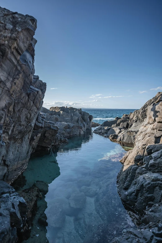 a body of water sitting on top of a rocky shore, pools, clear blue water, views to the ocean, traverse