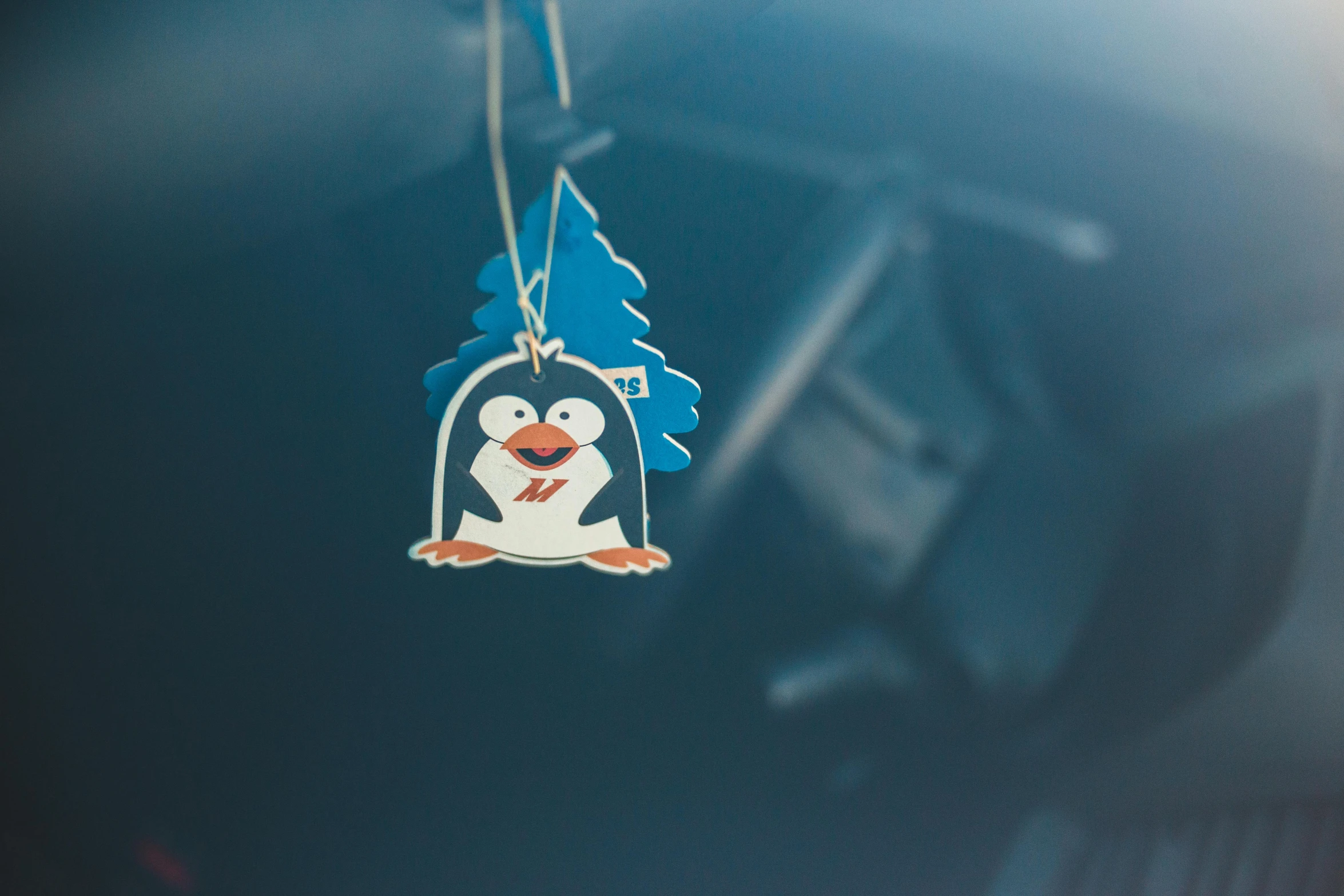 a car air freshener with a penguin on it, by Julia Pishtar, low - angle shot, festive, endangered, tag