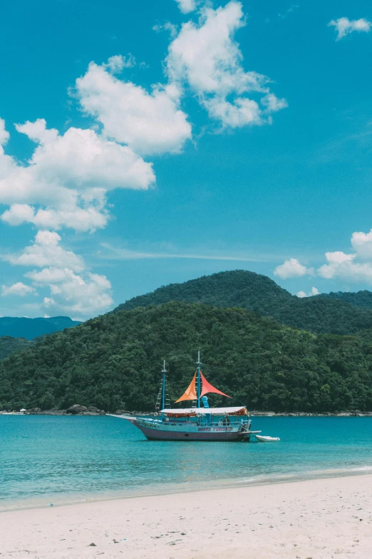 a boat sitting on top of a beach next to the ocean, sumatraism, mountainous jungle setting, water surrounds the ship, summer vibe, teal sky