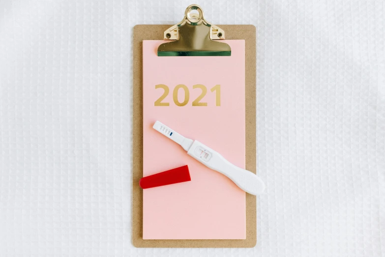 a clipboard with a pen sitting on top of it, a picture, by Julia Pishtar, trending on pexels, happening, contracept, new years eve, pink body, 2 0 2 1