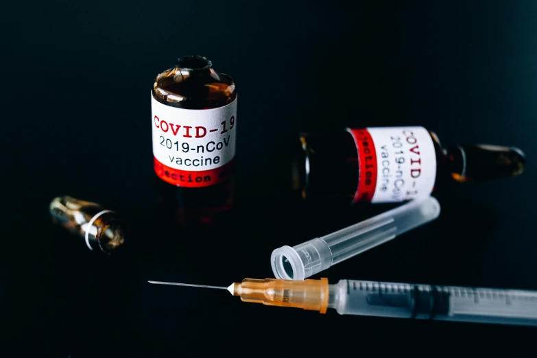 a syll sitting on top of a table next to a bottle of medicine, by Julia Pishtar, pexels, syringe, poster of corona virus, with a black background, set against a white background