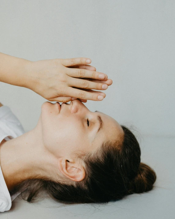 a woman laying on the ground with her hands on her head, trending on pexels, skincare, facing each other, bed, close-up of thin soft hand