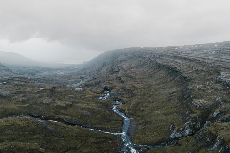 a river running through a lush green valley, by Jesper Knudsen, pexels contest winner, hurufiyya, under a gray foggy sky, 4 k cinematic panoramic view, barren tundra, marsden