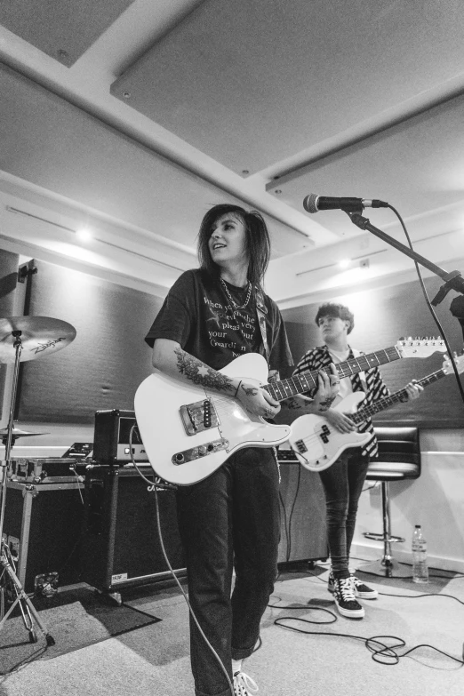 a group of people playing guitars in a room, a black and white photo, by Billie Waters, charli bowater, iren horrors, performing, detailed »