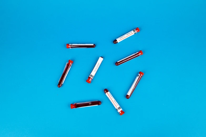 a group of red lipstick sitting on top of a blue surface, a picture, medical supplies, thumbnail, syringes, aesthetic shot