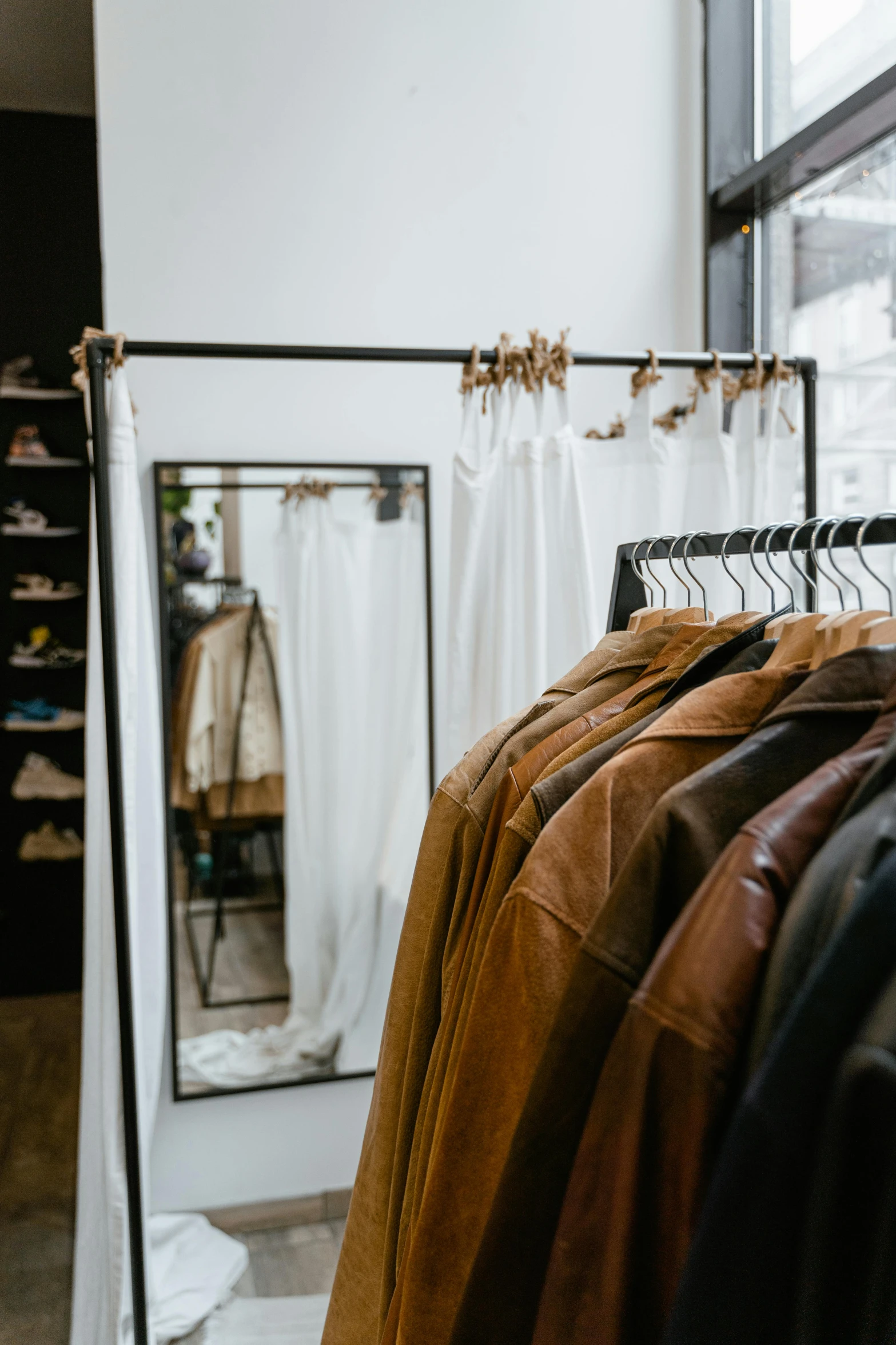 clothes hanging on a rack in a clothing store, trending on unsplash, in a brown leather maxi jacket, thumbnail, white clothing, storefront