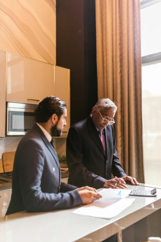 a couple of men standing next to each other in a kitchen, pexels contest winner, renaissance, kurdish lawyer, working in an office, george soros full body shot, wearing a suit and glasses