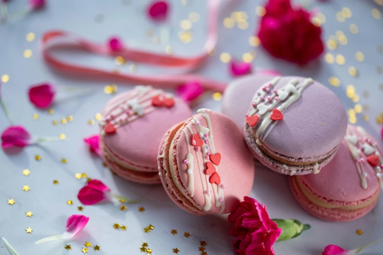 a couple of macarons sitting on top of a table, a picture, ribbons and flowers, pink hearts in the background, thumbnail, shot with sony alpha