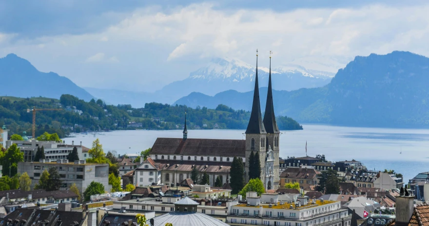 a view of a city with mountains in the background, by Karl Stauffer-Bern, pexels contest winner, lead - covered spire, vallejo, kara walker, lake view