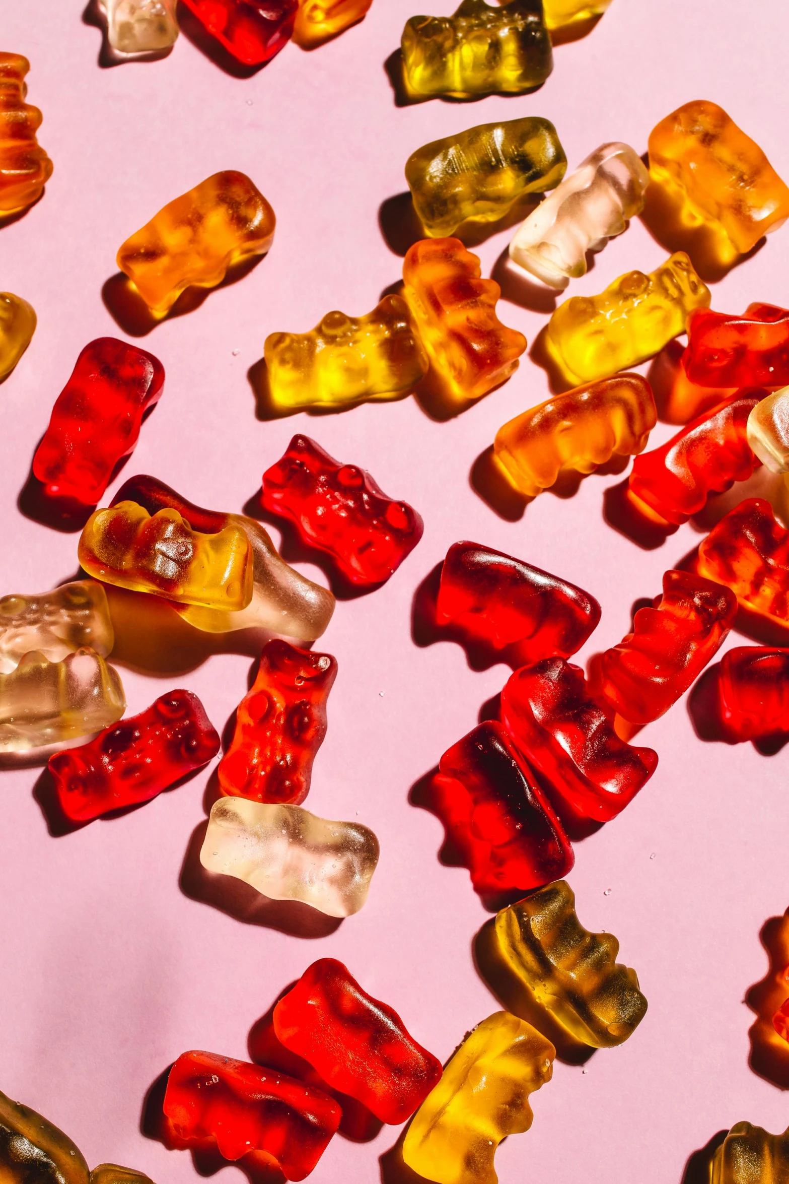 a pile of gummy bears sitting on top of a pink surface, by Julia Pishtar, trending on pexels, red yellow, made of food, licking out, corduroy