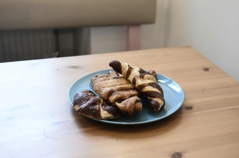 a blue plate topped with pastries on top of a wooden table, sandworm, けもの, brown, thumbnail